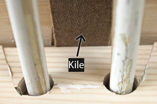 Samling med "kile" i gulvbræt: Mens limen tørrer, sættes kilen i spænd ved at trykke en afstandskile forsigtigt ned mellem kile og væg Samling med "kile" i gulvbræt: Mens limen tørrer, sættes kilen i spænd ved at trykke en afstandskile forsigtigt ned mellem kile og væg